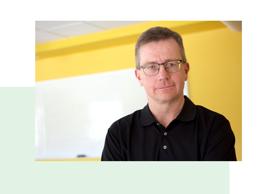 Dr. Tom Bateman in a STU classroom with yellow walls and a white board