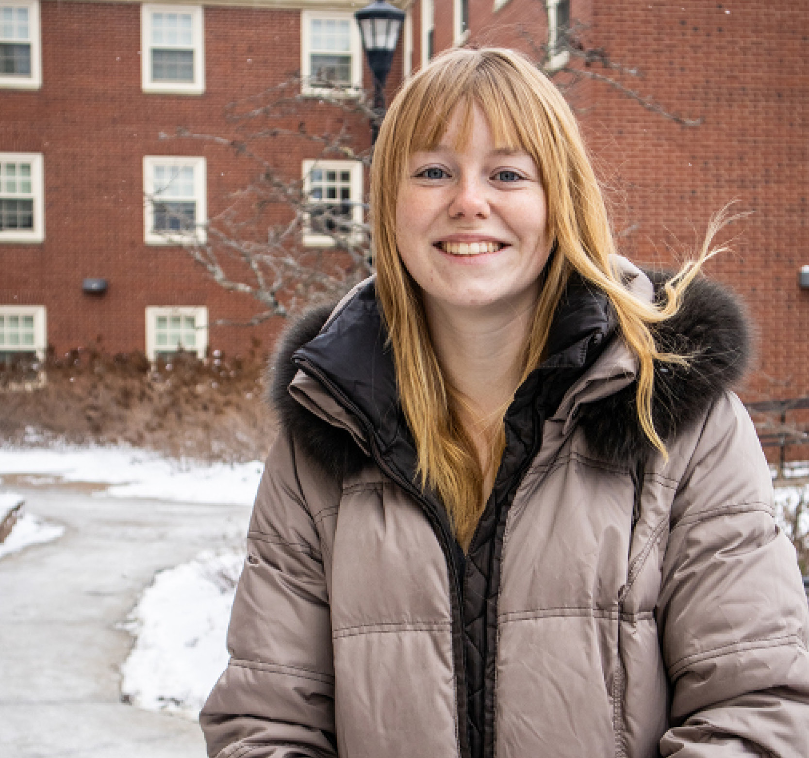 Student intern Laura next to campus buildings in winter