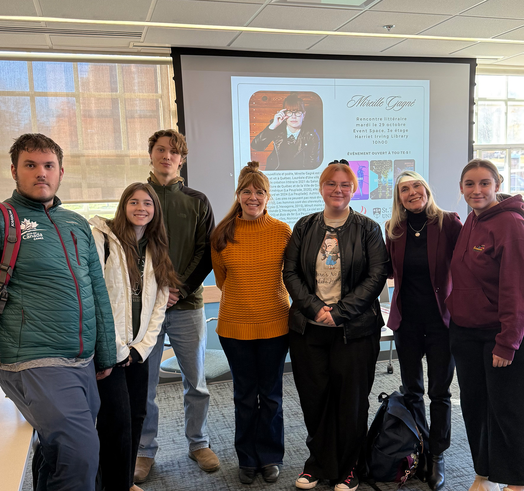 A group of students stand together with French author Mirielle Gagne