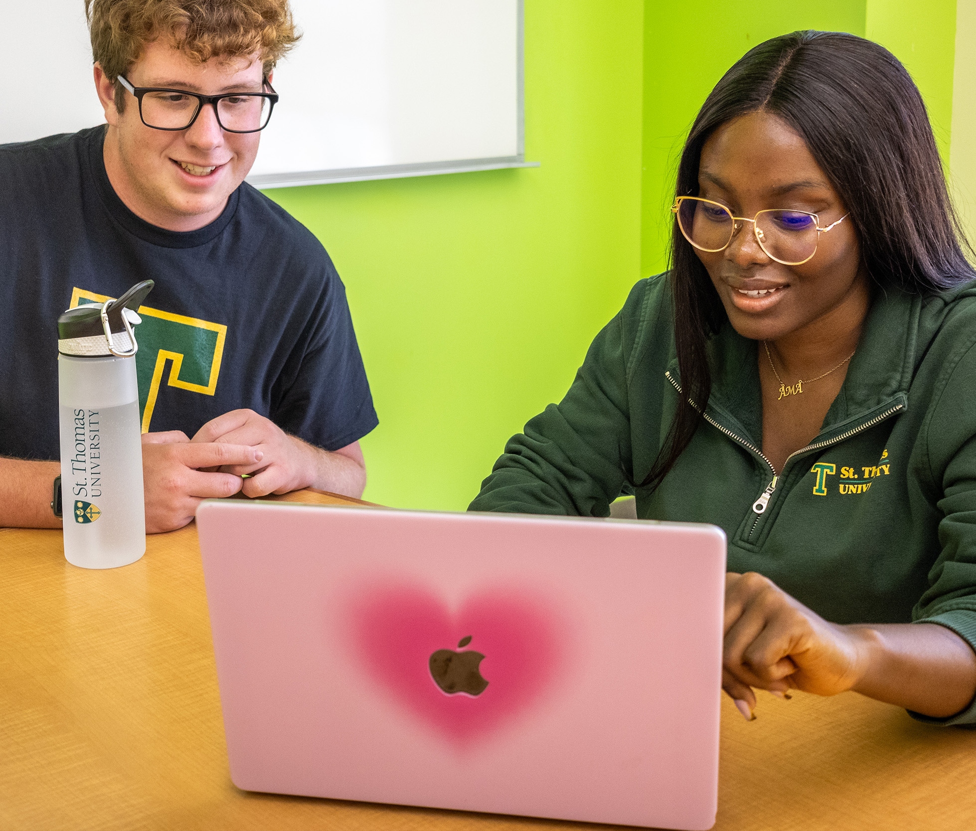 A male and female student look at a laptop together