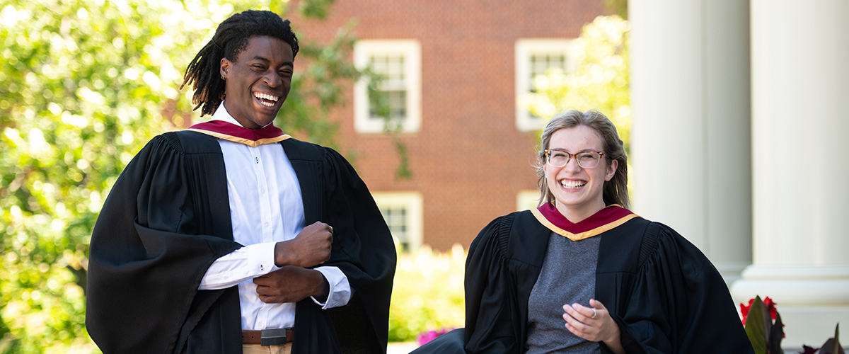 Two graduates in robes laughing