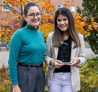 STU Experiential learning staff Clara and Ale holding glass trophy on campus