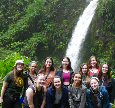 Group of students on trip in Costa Rica with waterfall in background