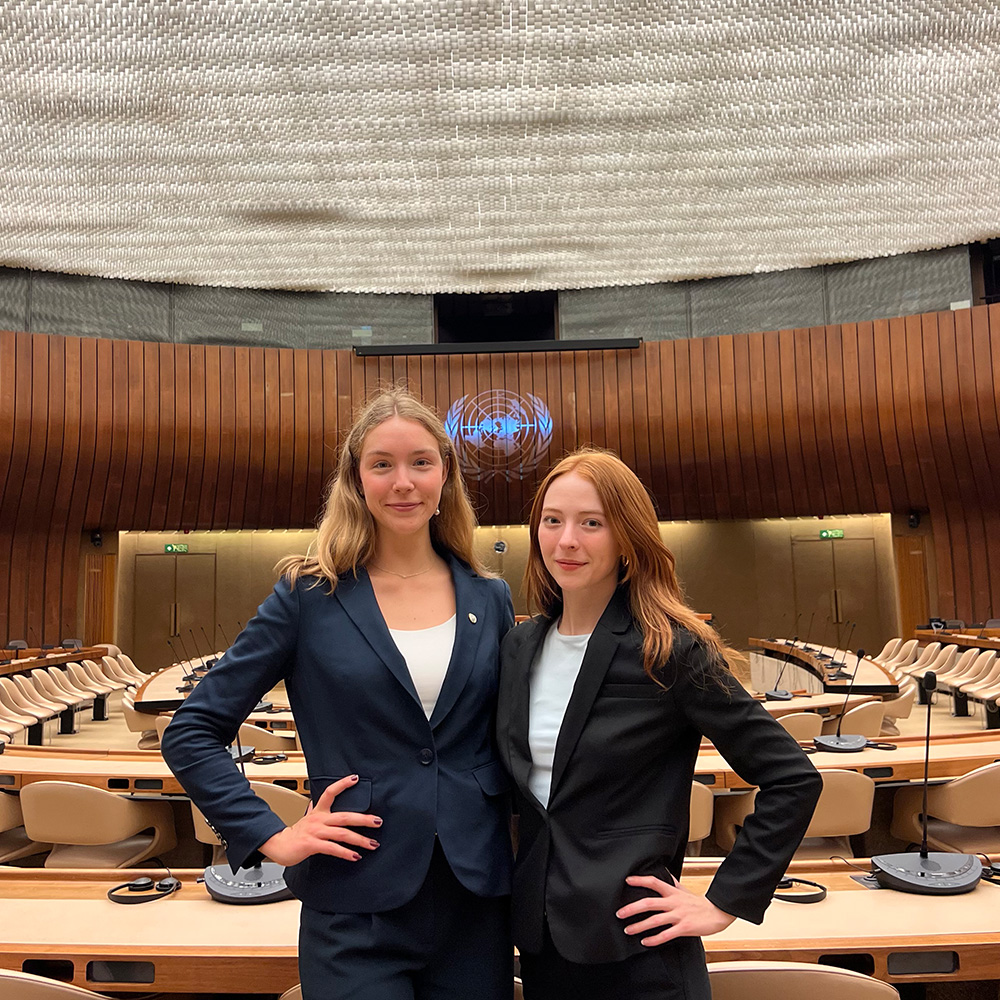 Two female students wearing black pant suits stand in the United Nation's Palais des Nations in Geneva