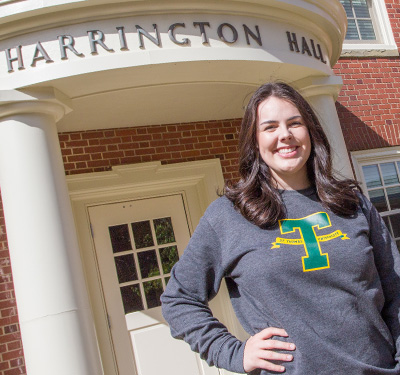 A photo of a student in a T hoodie outside of Harrington Hall, STU Campus