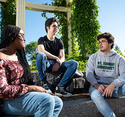Three students sitting on steps outside.