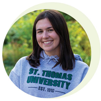 a round photo of julia evans wearing a STU hoodie outside.