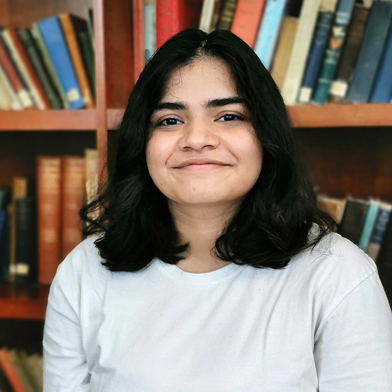 A student sitting in front of a bookshelf