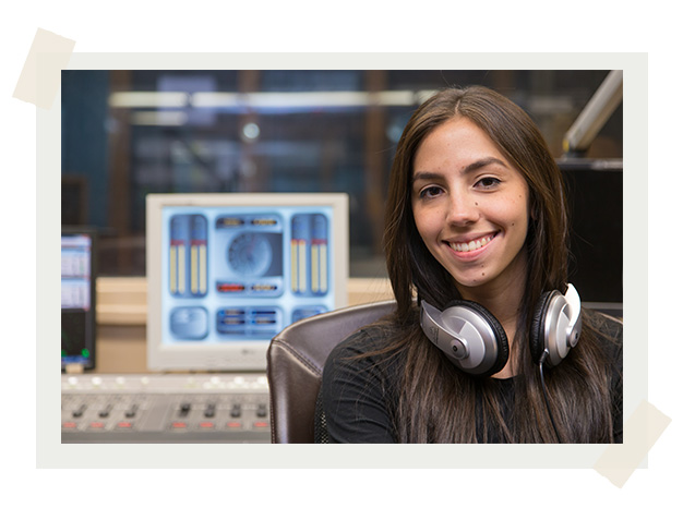 A student wearing headphone around her neck in a recording studio.