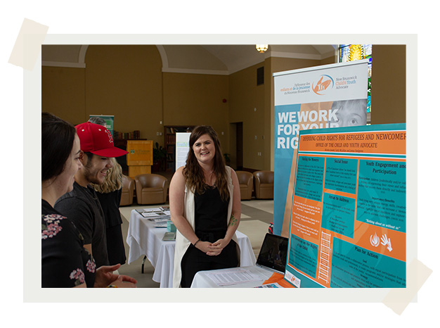 Students talk to a representative from the New Brunswick Child and Youth Advocate's Office at a career fair in the Great Hall